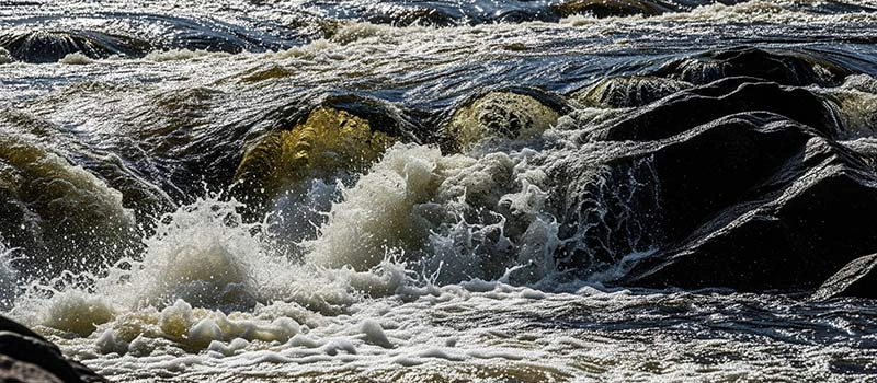Wasser spritzt über die Felsen der Vindelforsarna Stromschnellen.